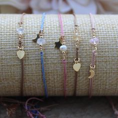 four bracelets with charms and hearts on them sitting next to a roll of fabric