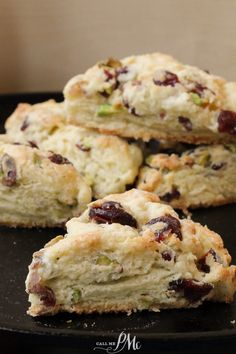 several scones with cranberries and other toppings on a black plate