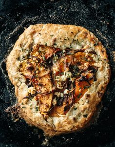 an artisan pizza with onions, cheese and herbs on a black surface top view from above