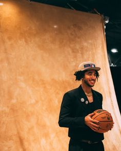 a man holding a basketball in front of a wall