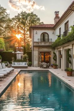 an outdoor swimming pool with lounge chairs and trees in the background at sunset or dawn