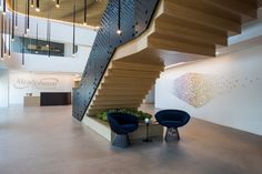 two blue chairs sitting in front of a spiral stair case next to a planter