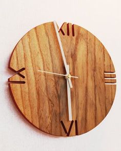 a wooden clock with roman numerals is shown on a white surface and shows the time