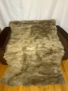 a brown and white fur rug sitting on top of a wooden floor next to a chair