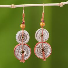 the earrings are hanging from a wire on a branch with green leaves in the background