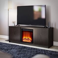 a flat screen tv sitting on top of a wooden entertainment center next to a fire place