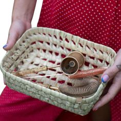 a woman is holding a basket with various items in it