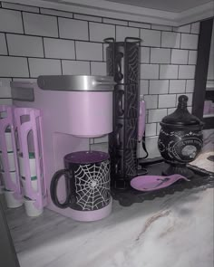 a kitchen counter topped with purple coffee mugs and other items on top of it