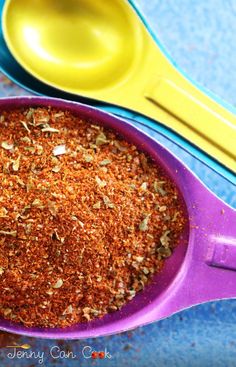 a purple bowl filled with spices next to two yellow spoons