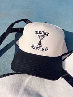 Whether you're sipping martinis under the palm trees or lounging by the pool, let this hat be your go-to accessory for the best summer vibes, one bikini and martini at a time! Adjustable Flat Brim Trucker Hat For Summer, White Hat For Poolside Vacation, Summer Trucker Hat For Vacation In Spring, Trendy Adjustable Hat For Sunbathing, Trendy Brimmed Summer Trucker Hat, Trendy Brimmed Trucker Hat For Summer, Fun Flat Brim Trucker Hat For The Beach, Trendy Adjustable Bucket Hat For Vacation, Flat Brim Trucker Hat For Summer Beach