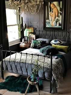 a bedroom with a metal bed frame and chandelier hanging from it's ceiling