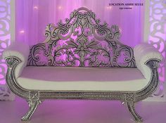 a white couch sitting in front of a purple wall with lights on it's sides