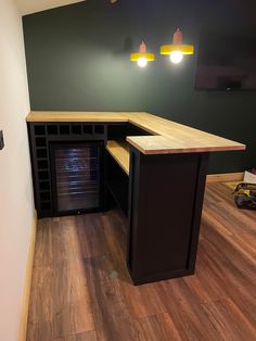 an empty room with wood flooring and dark green walls, two lights above the counter