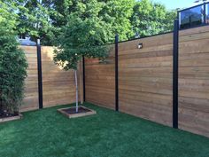 a wooden fence in the middle of a yard with grass and trees on both sides