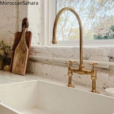 a kitchen sink sitting under a window next to a cutting board