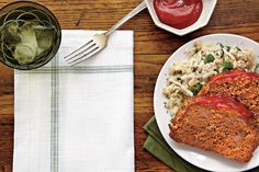 meatloaf with tomato sauce and macaroni salad on a plate next to a glass of water