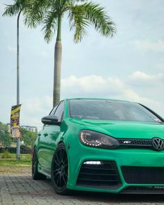 a green vw golf gtr parked in front of a palm tree