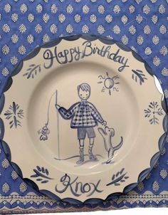 a blue and white plate with an image of a boy holding a dog on it