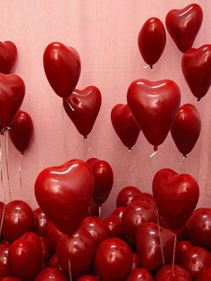 there are many red heart shaped balloons floating in the air with strings attached to them