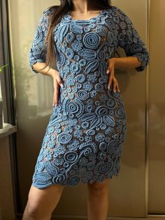 a woman standing in front of a glass door wearing a blue dress and black heels