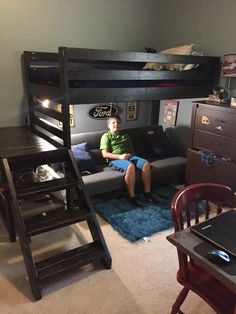 a young boy sitting on top of a couch in front of a bunk bed with stairs