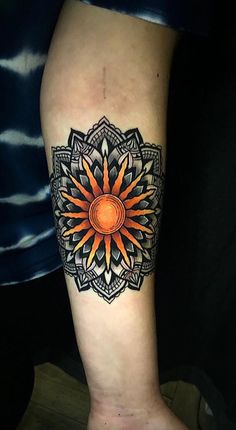 a person with a tattoo on their leg that has an orange flower in the center