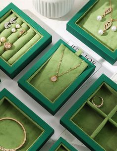 several green boxes with jewelry in them sitting on a table