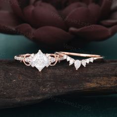 two wedding rings on top of a piece of wood with a flower in the background