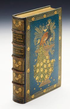 an antique book with gold trimming and blue cover, featuring a peacock on it