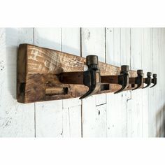 an old wooden coat rack with five bottles hanging from it's hooks on a white wall