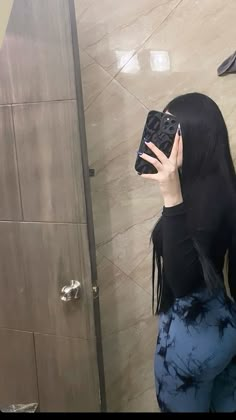 a woman with long black hair is taking a selfie in front of a mirror