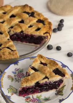 a blueberry pie on a plate with one slice cut out and the rest half eaten