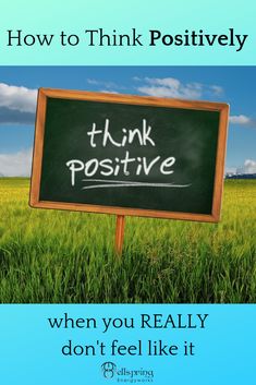 a blackboard with the words think positive written on it in front of green grass