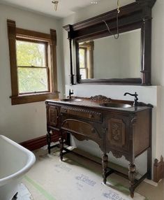 a bathroom with a sink, mirror and bathtub in the middle of the room