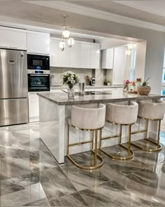 a kitchen with marble flooring and gold bar stools next to an island in the middle