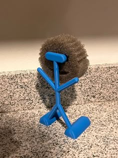 a blue object sitting on top of a counter next to a black ball and brush