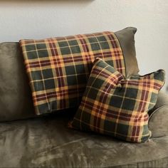 two pillows sitting on top of a couch next to each other in front of a painting