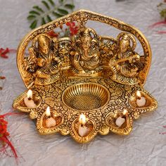 an intricately decorated brass tray with candles in the shape of ganesha on it