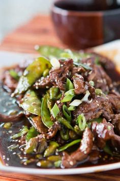 a white plate topped with meat and veggies on top of a wooden table