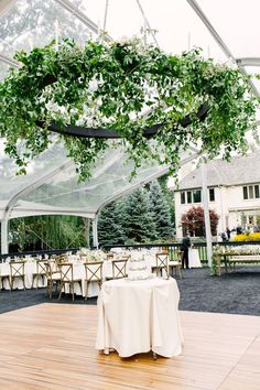 an outdoor dining area with tables, chairs and greenery hanging from the ceiling above