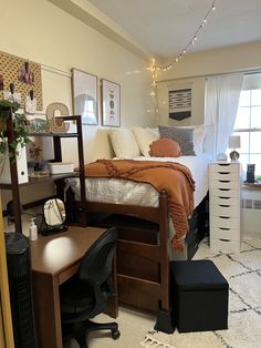 a bed room with a neatly made bed next to a window and a desk in front of it