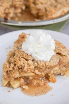 a slice of pie with whipped cream on top and another pie in the back ground