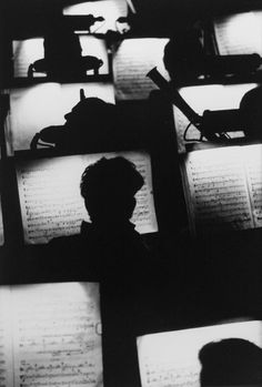 black and white photograph of people looking at sheet music on computer screens in dark room