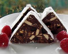 a piece of chocolate cake with white icing and raspberries on the side