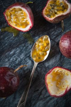 a spoon with some food on it next to two pieces of pomegranate