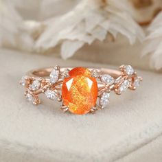 an orange and white ring sitting on top of a piece of cloth next to flowers