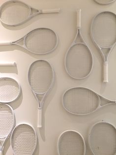 several tennis rackets are lined up on the wall, all in different shapes and sizes