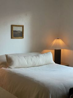 a white bed sitting next to a lamp in a bedroom