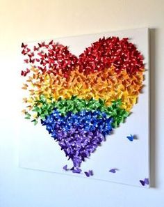 a heart made out of colored butterflies on a white wall with the word love spelled in it