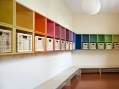 the colorful shelves are lined up against the white wall in the room with many baskets on them